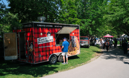 Food vendor at a BBQ showing a cooked chicken leg