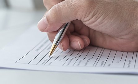 Hand holding a pen filling out a form.