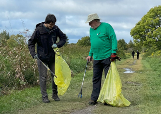 two people outdoors picking up garbage