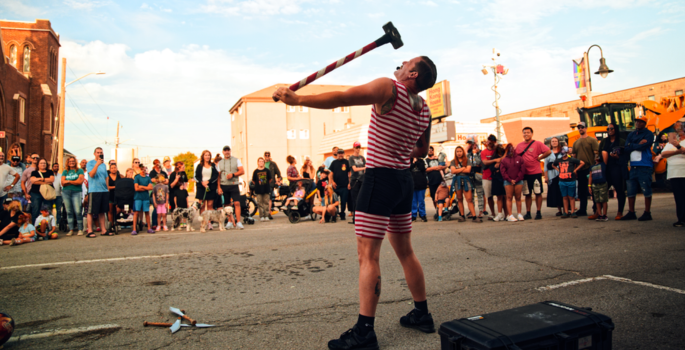 on-street strongman performer balancing a sledge hammer