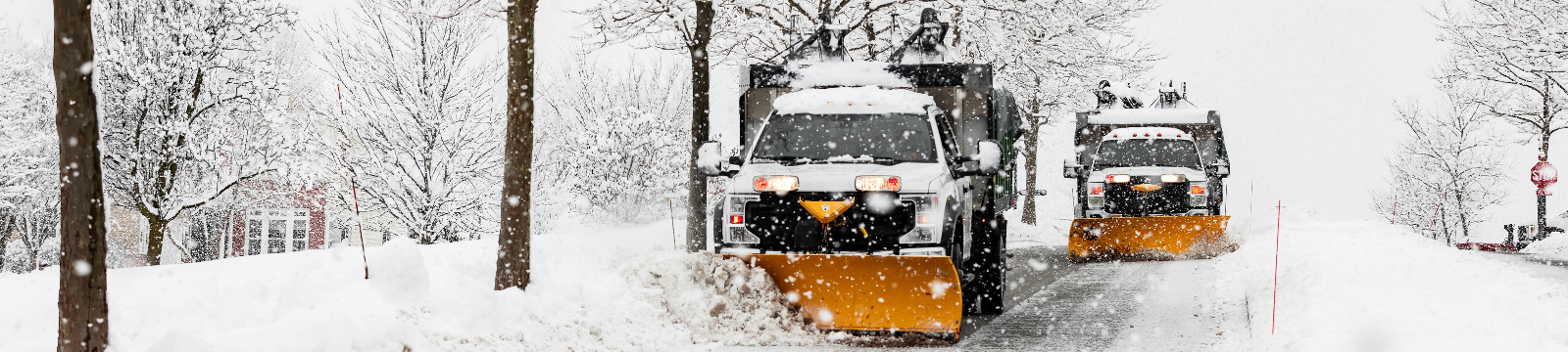 two yellow plows drive down a street